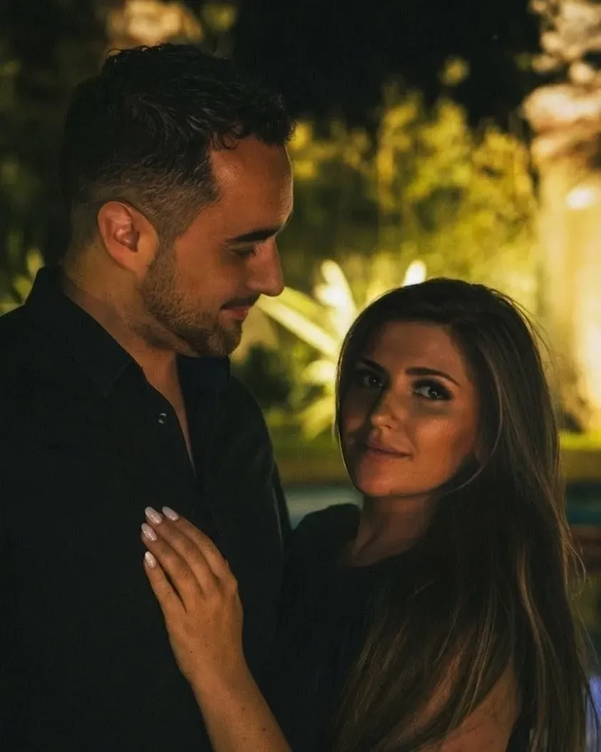 Laetitia and Erwann at night in a lit garden; he looks at her, she looks at the camera.